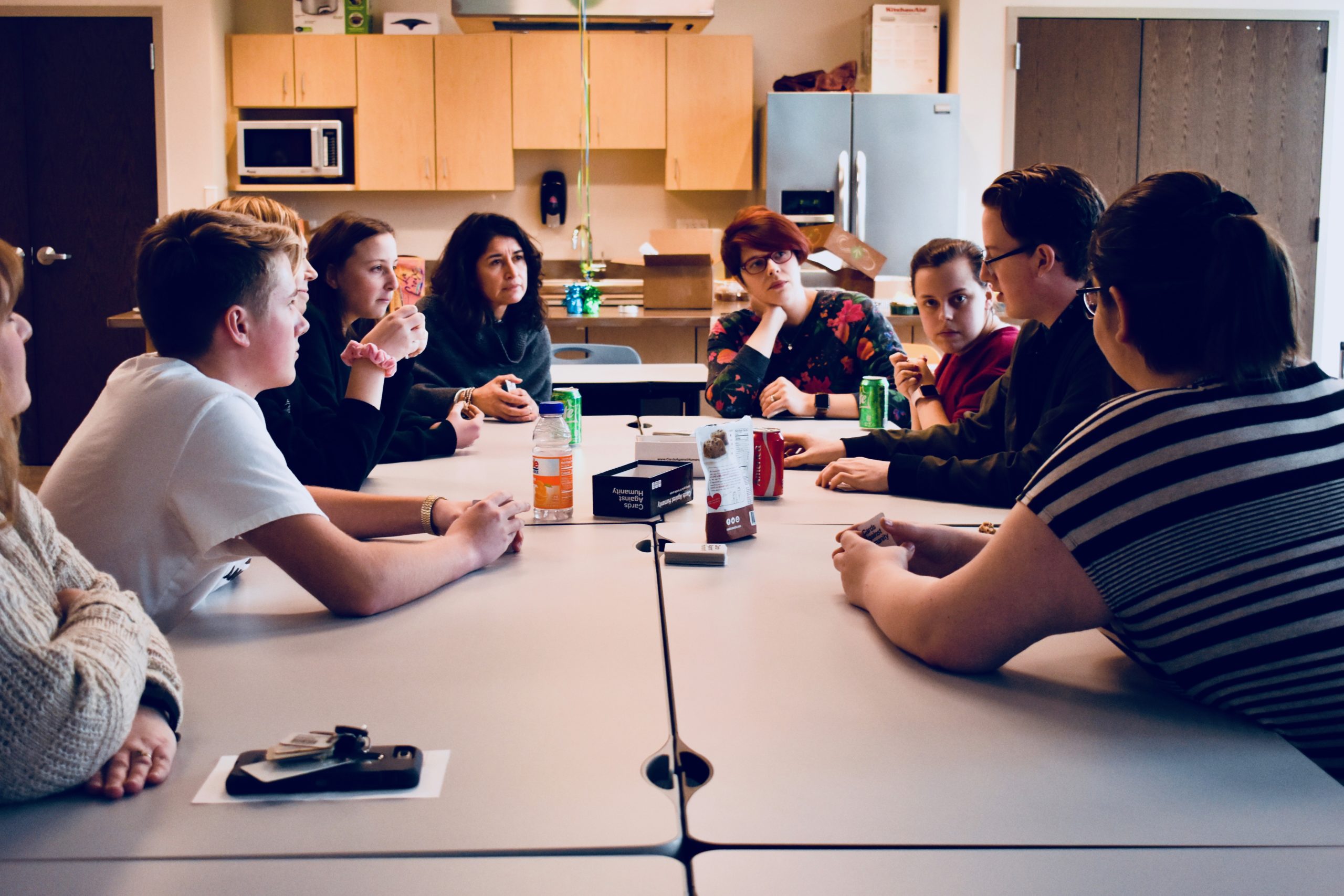 Group of young adults sit around a conference table talking