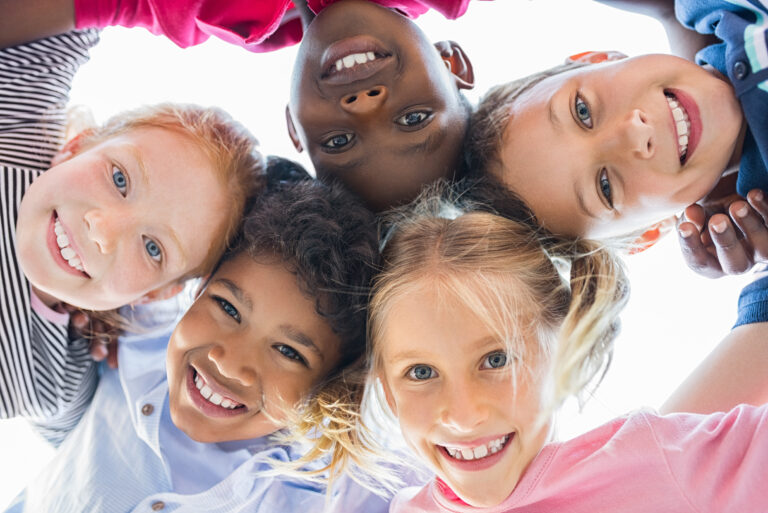 Closeup face of happy children embracing each other and smiling at camera.