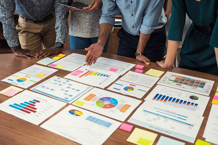 Closeup business man and businesswoman hands understanding pie and bar graphs during meeting.
