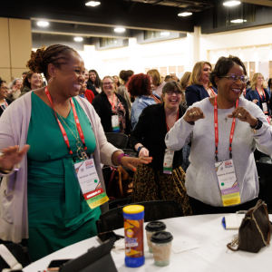 Past AMCHP conference attendees dancing and smiling during a plenary session.
