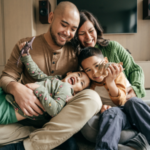 Family sitting in living room smiling at each other.