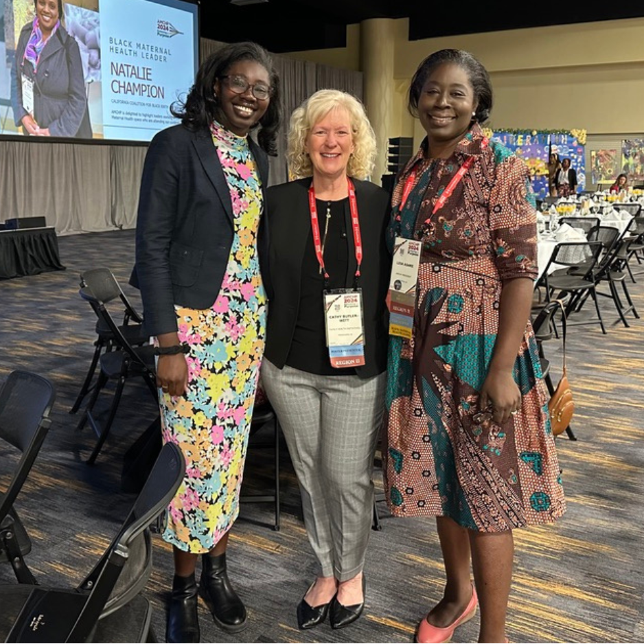 Three women, including Cathy Butler-Witt, pose and smile at the camera at the AMCHP Conference.