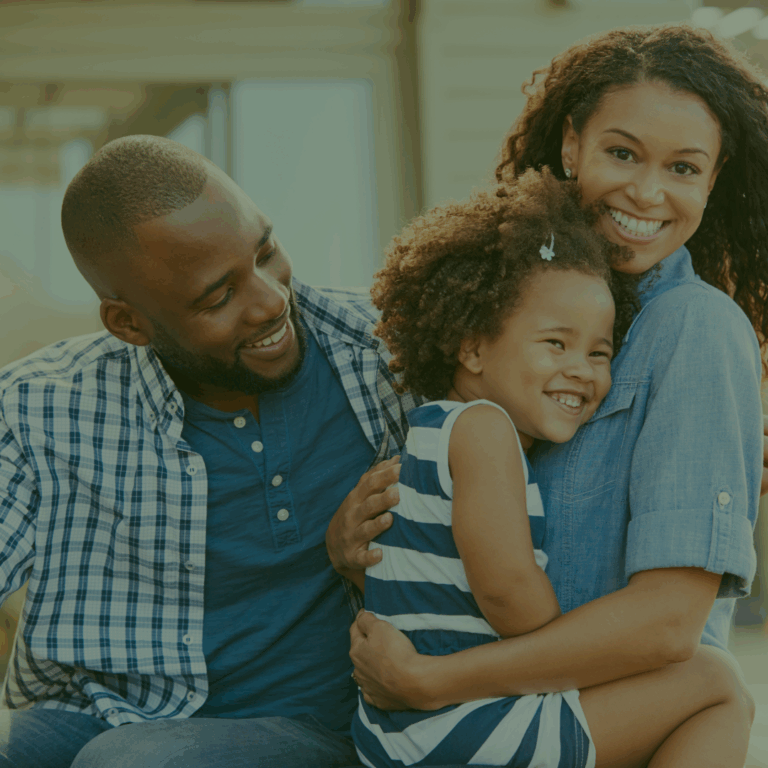 Family embracing outdoors smiling to camera.