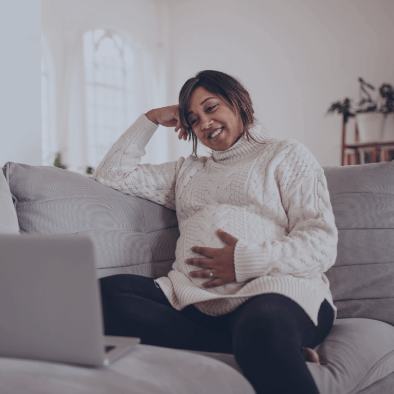 Pregnant mother on sofa looking at laptop