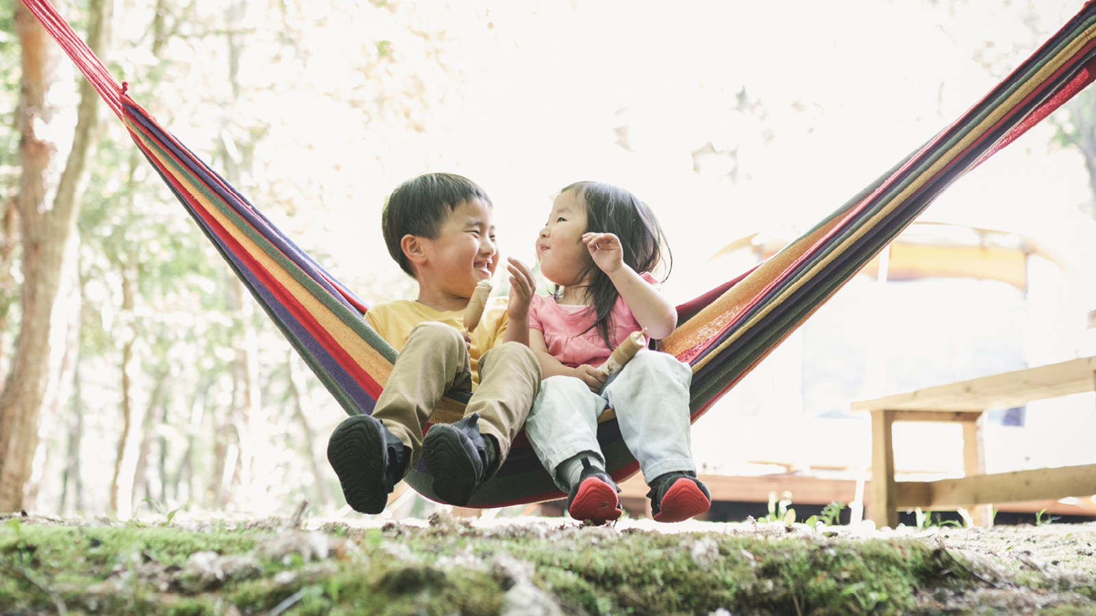 Two children sitting on a hammock