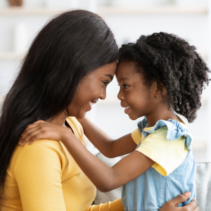 Mother holding her young duaghter facing each other and smiling